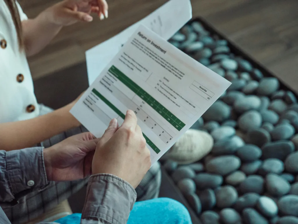 Two people reviewing a printed ROI (Return on Investment) assessment form with green and white sections.