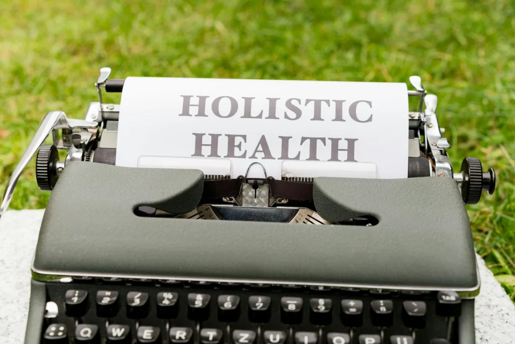 A typewriter with a sheet of paper displaying the words “HOLISTIC HEALTH.”