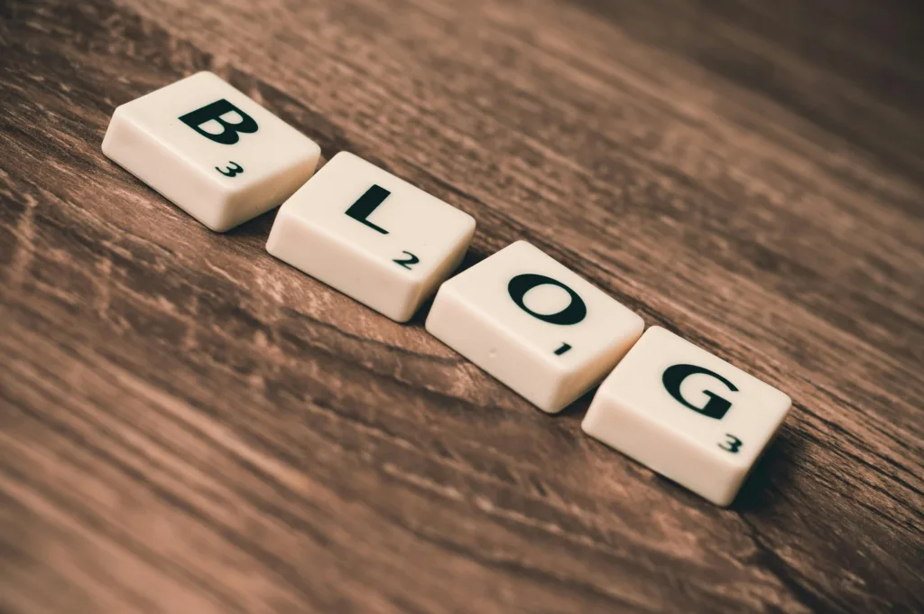 Letter tiles on a wooden surface spelling the word “BLOG.”