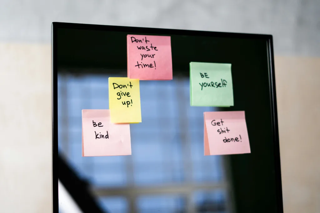 Sticky notes on a screen with handwritten motivational messages such as “Don’t waste your time,” “Be kind,” and “Don’t give up.”