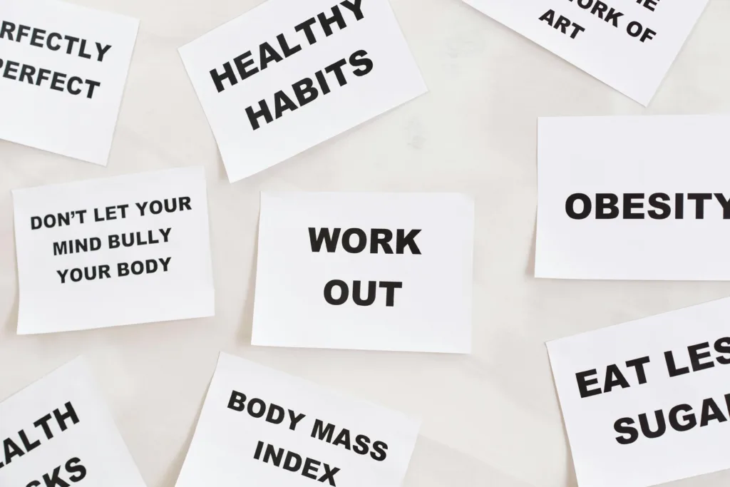 Printed cards with health-related phrases including “Healthy Habits,” “Work Out,” and “Body Mass Index” arranged on a surface.