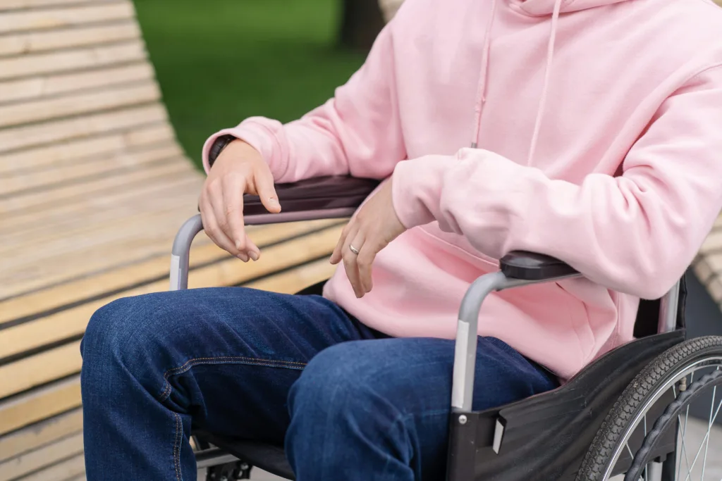 Person wearing a pink hoodie sitting in a wheelchair outdoors