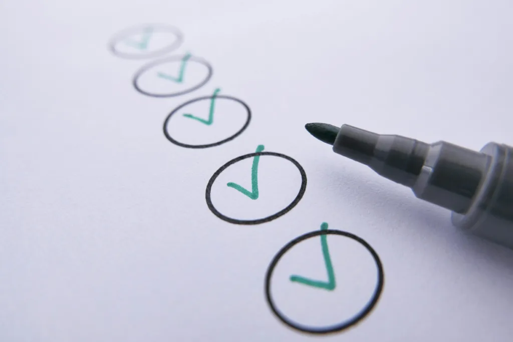Close-up of an uncapped pen next to several circles with green tick marks inside each one.