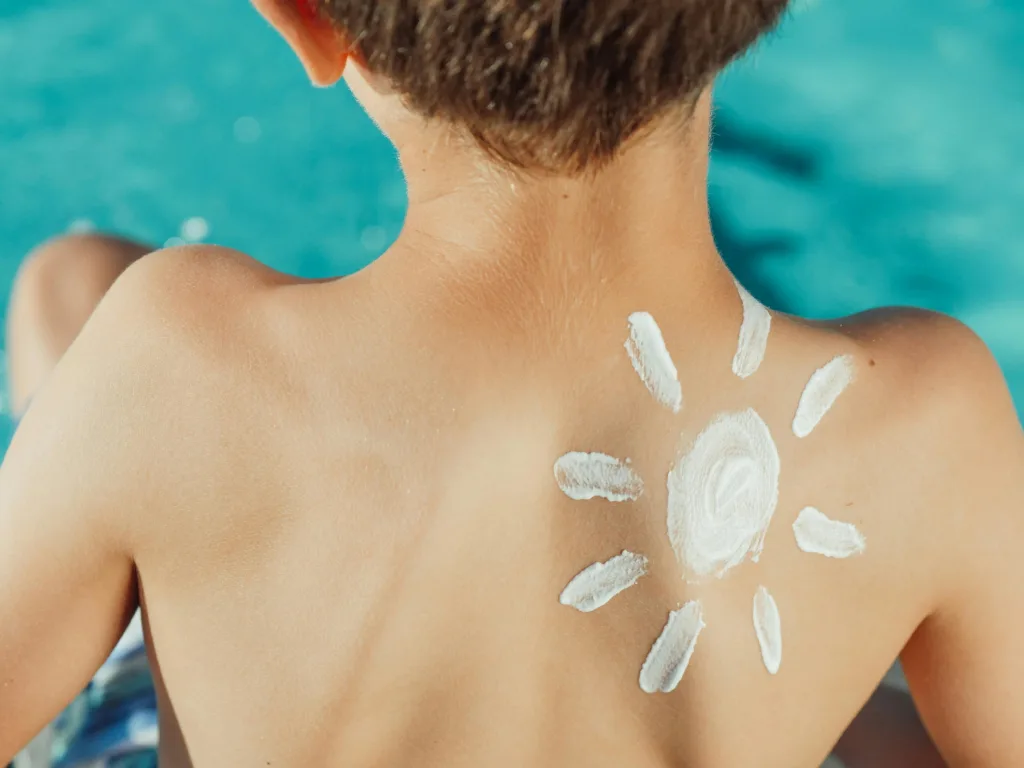 A child’s back with suncream drawn in a cartoon sun shape.