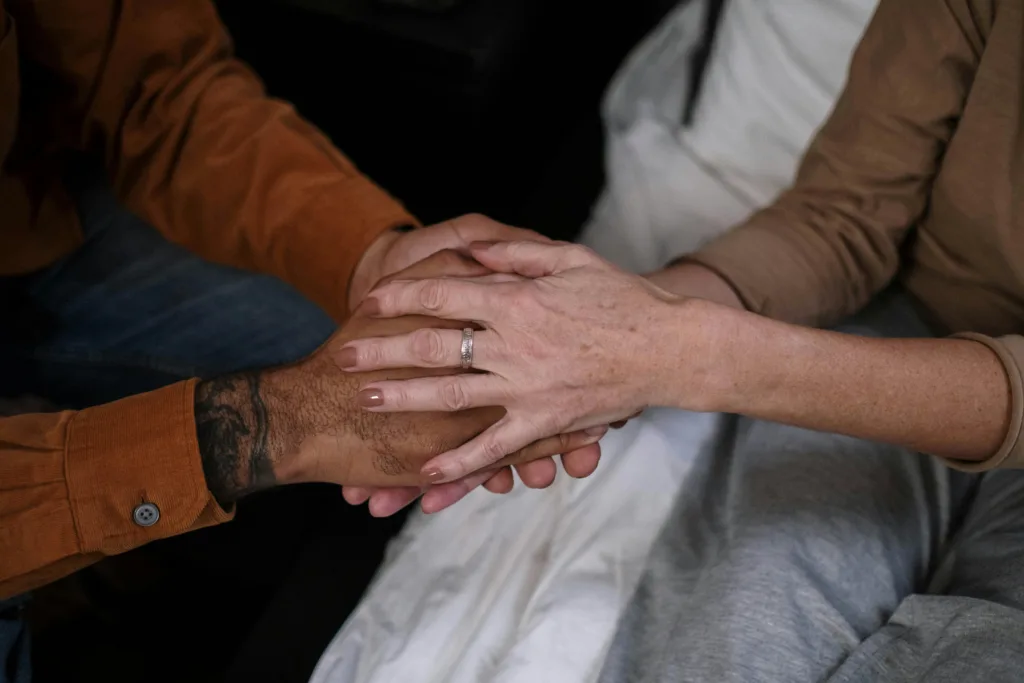 Close up of two people holding hands. Their hands are stacked, fully covering each other.