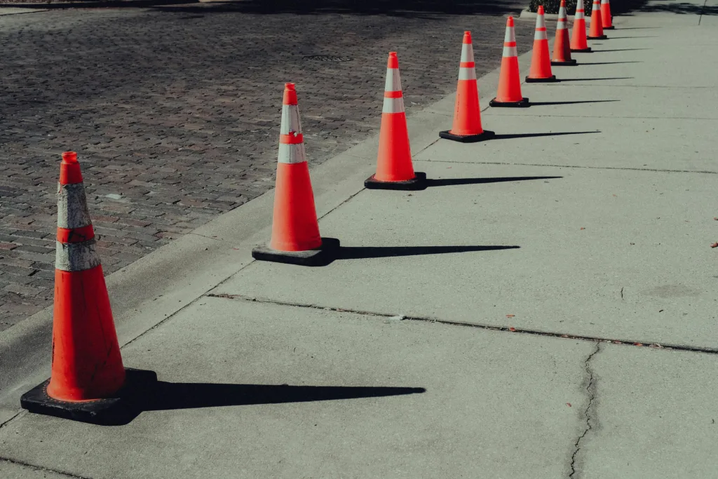 A street lined by a row of orange and white striped traffic cones.