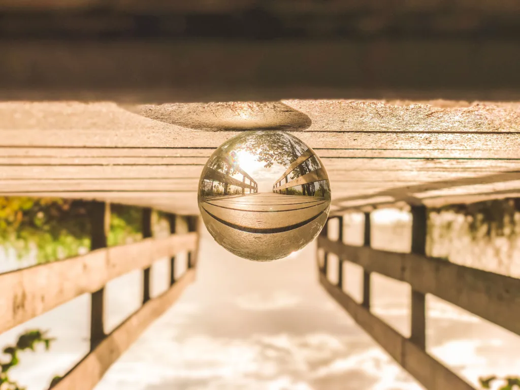 Upside-down image of a glass ball on a wooden deck. The reflection in the glass ball is right-side-up.