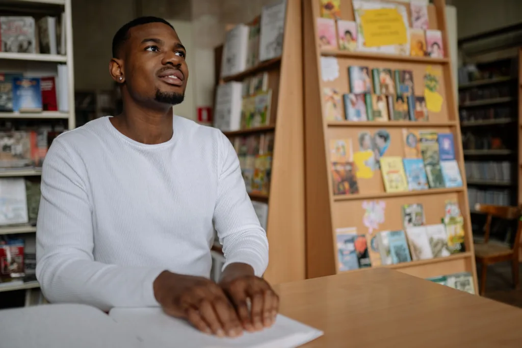 Black man reading a Braille book in a library.