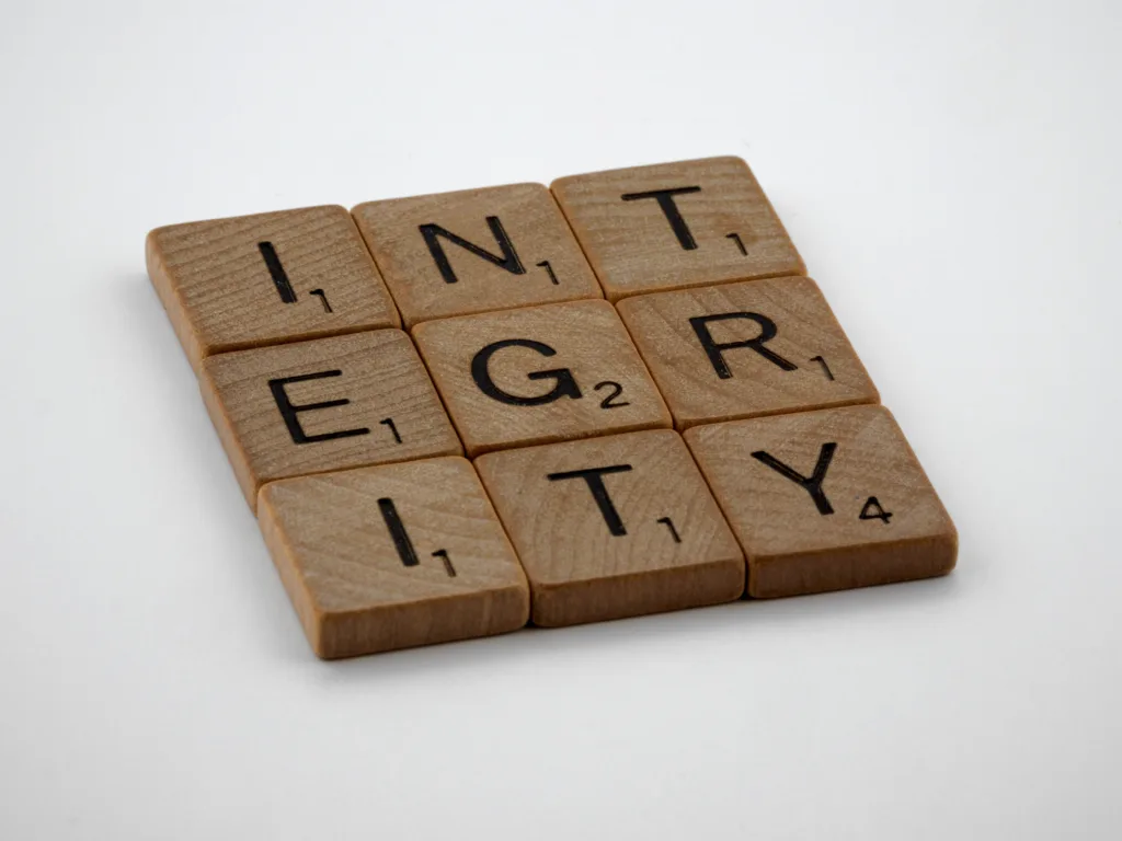 Wooden scrabble tiles spelling 'INTEGRITY' on a white background, emphasising honesty and ethics