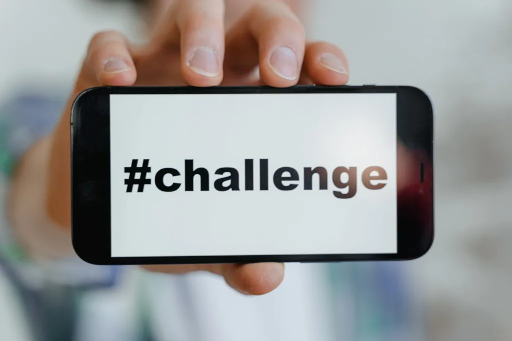 Close-up of a hand holding a smartphone displaying a '#challenge' hashtag