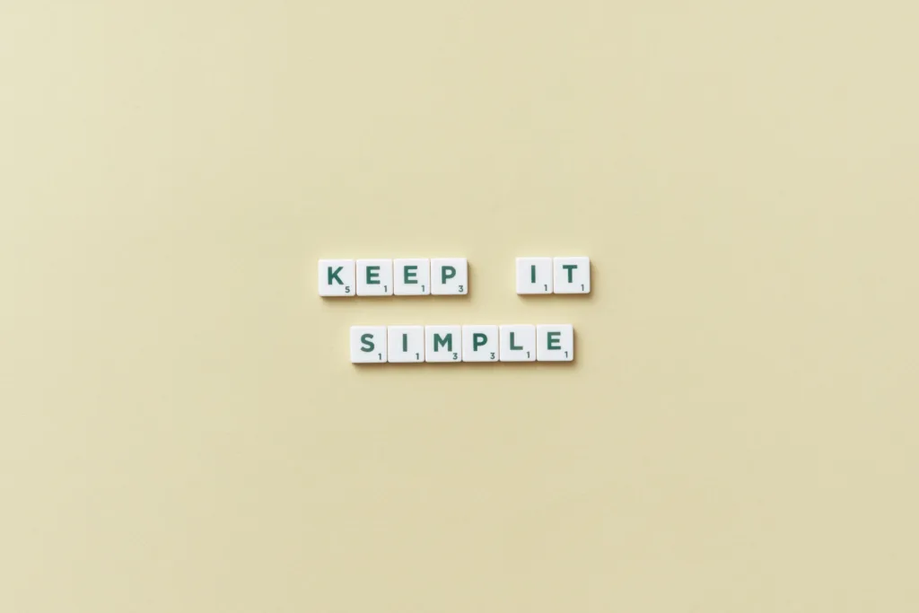 Scrabble tiles spelling out 'Keep It Simple' on a beige background.