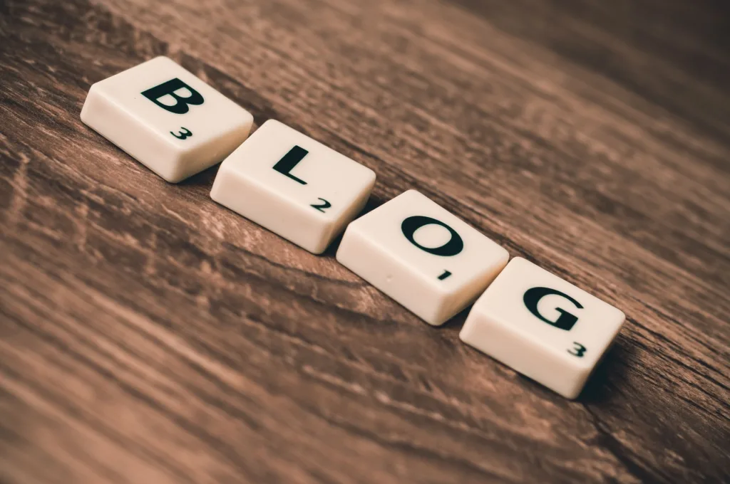 Letter tiles spelling ‘Blog’ on a wooden background.
