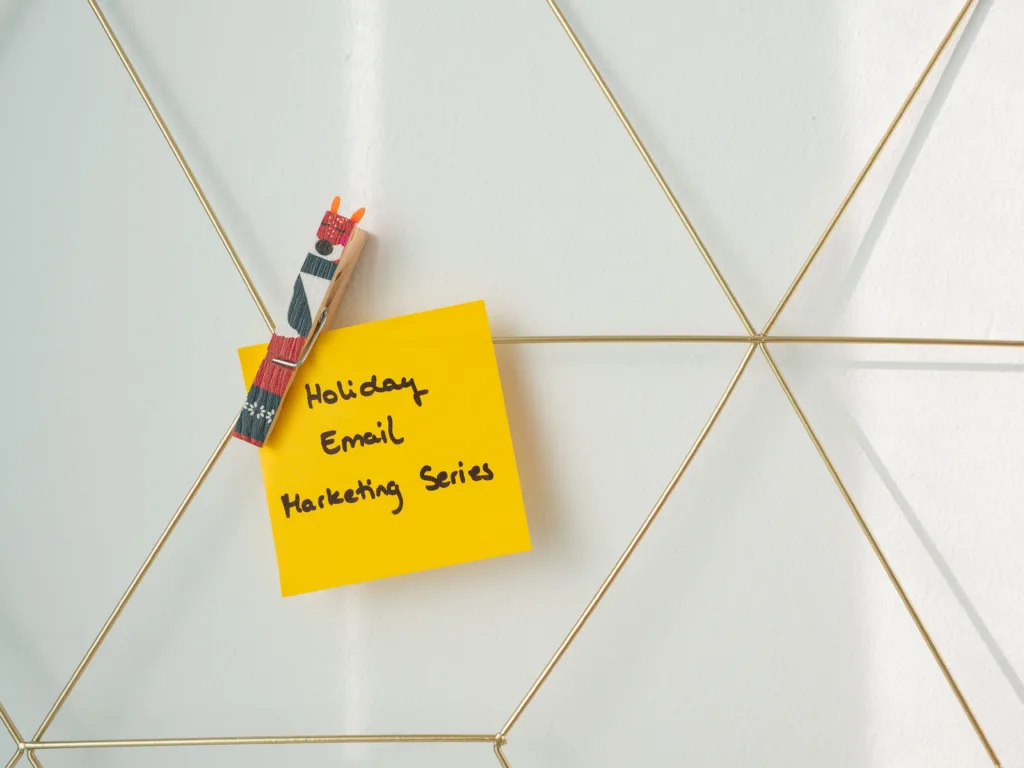 Bright yellow sticky note with the text 'Holiday Email Marketing Series' clipped to a wireframe wall.